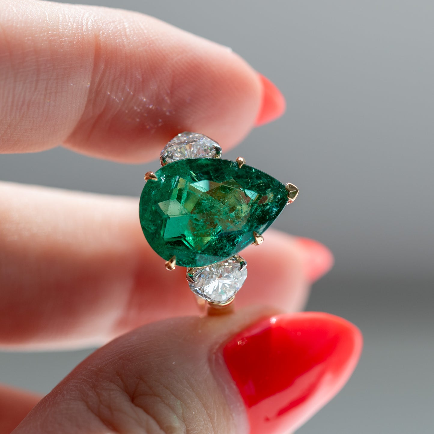 Show-stopping 5.65ct green pear cut emerald ring with heart shape diamonds in 18k gold by Valentina Fine Jewellery Hong Kong. Free global shipping including USA