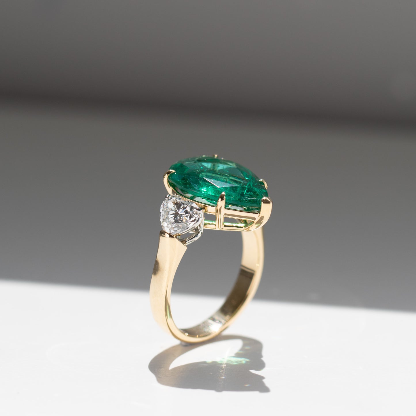 Show-stopping 5.65ct green pear cut emerald ring with heart shape diamonds in 18k gold by Valentina Fine Jewellery Hong Kong. Free global shipping including USA