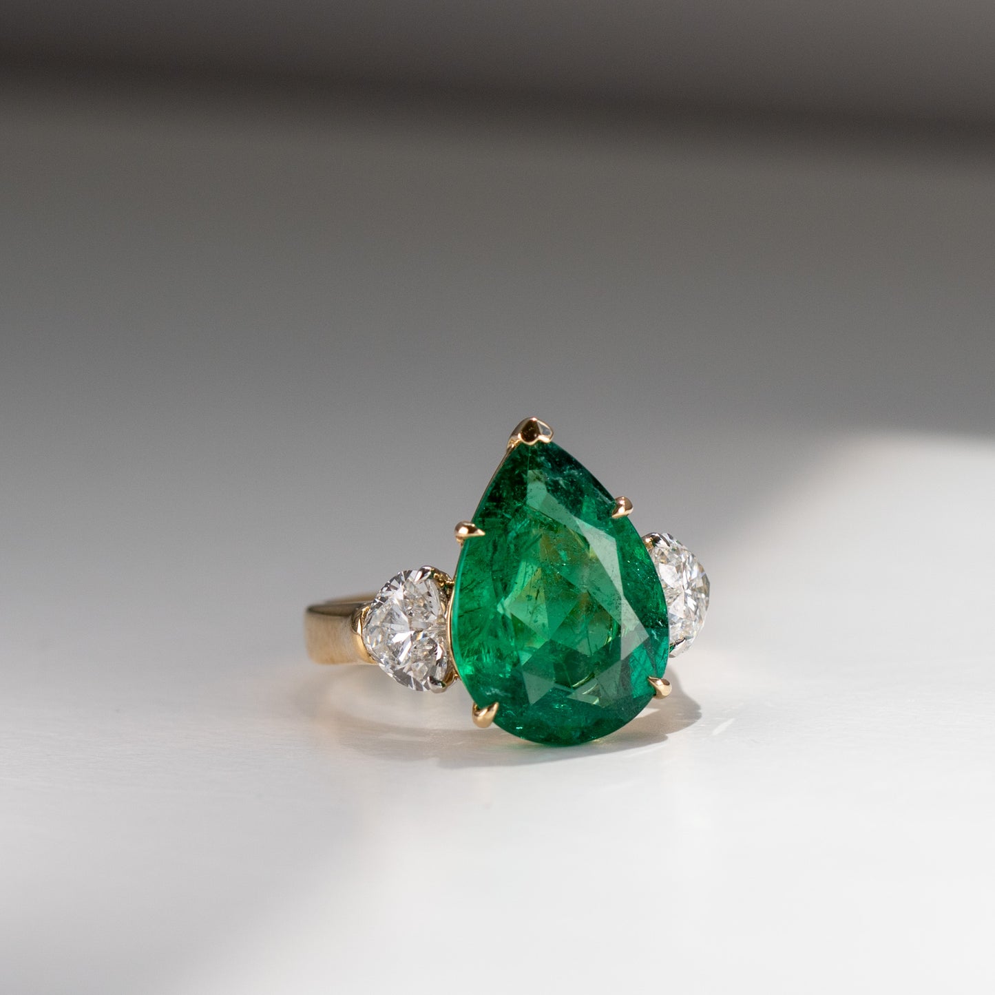 Show-stopping 5.65ct green pear cut emerald ring with heart shape diamonds in 18k gold by Valentina Fine Jewellery Hong Kong. Free global shipping including USA